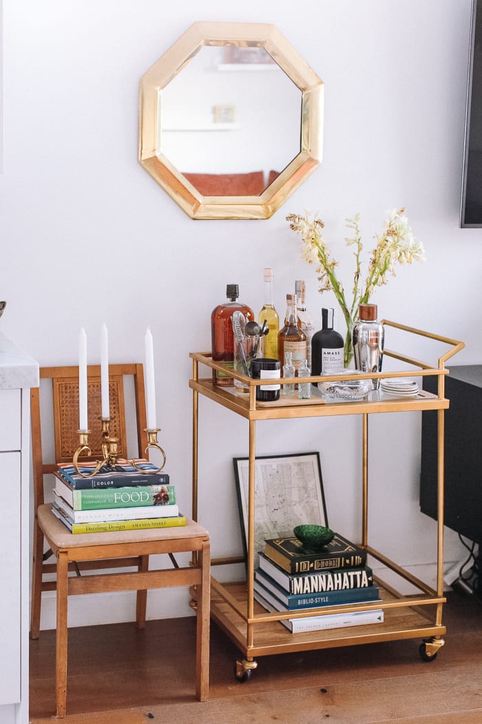 Chariot de bar cible, carte vintage de New York City, candélabre vintage. Bougie Byredo, vase pichet CB2, sous-verres Jonathan Adler, miroir vintage, chaise pliante vintage